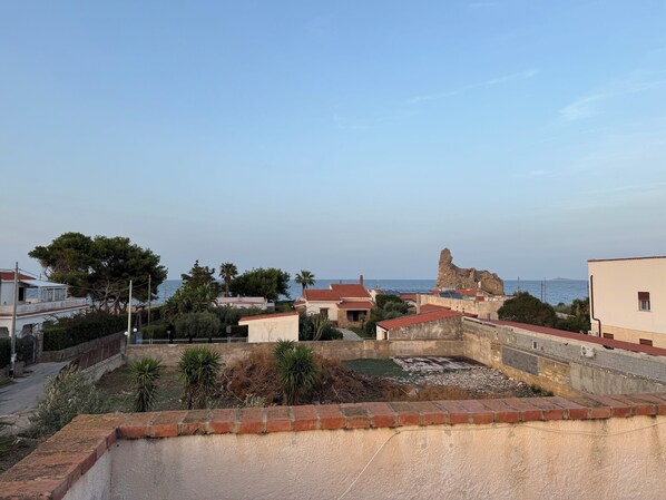 Une vue sur la côte, avec des bâtiments, un promontoire rocheux et un ciel dégagé.