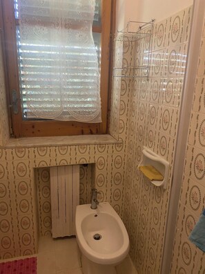 Une salle de bain avec une fenêtre, un lavabo et un porte-serviettes.