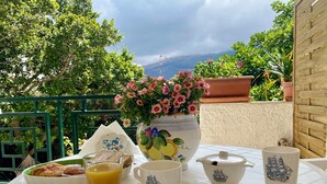 Une table dressée avec des aliments pour le petit-déjeuner, un vase de fleurs et une vue pittoresque.