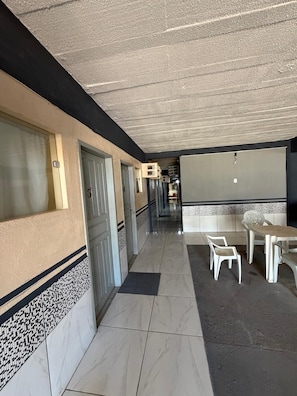 A corridor with doors, a tiled floor, and a seating area with chairs and a table. - Hotel Pousada Rocha budget-friendly (Nova Porto Velho Porto Velho)