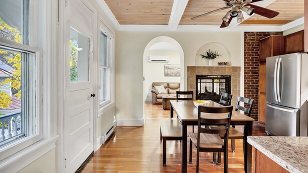 Una cocina moderna con refrigerador integrado, armarios de madera y un comedor con mesa y sillas.