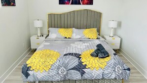 A bed with a floral bedspread, two bedside tables with lamps, a headboard, and a wall-mounted picture.