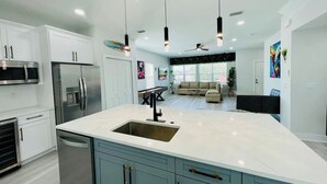 A modern kitchen with a central island, stainless steel appliances, and pendant lighting.