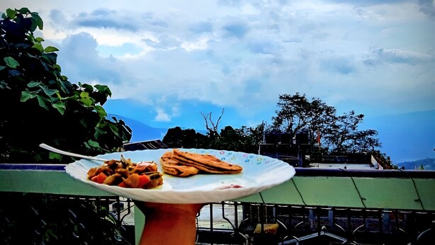 Un plato con comida en un balcón con vista al cielo y árboles.