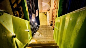 Una escalera con paredes verdes y una reja metálica en la parte superior.