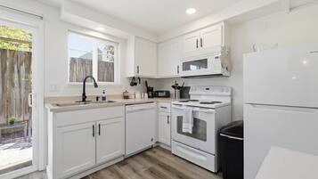 A modern kitchen with white cabinetry, a built-in oven, a microwave, and a dishwasher.