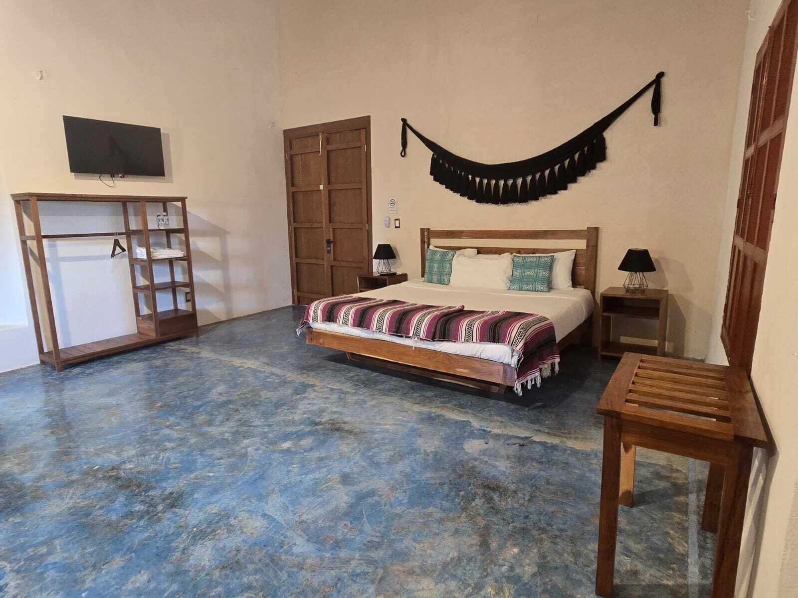 Une chambre avec un lit, une armoire, une télévision et un hamac.