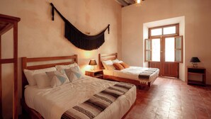 A bedroom with two beds, a hammock, and a window with shutters. - Hotel Boutique Casa Jade (Campeche)