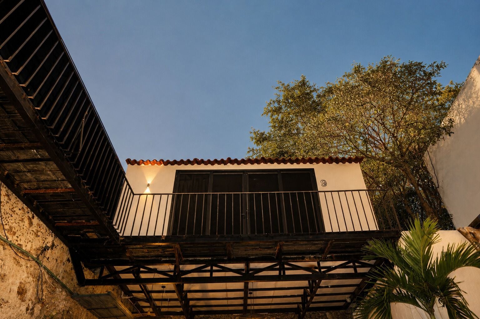A building with a balcony, a window, and a tree in the background.