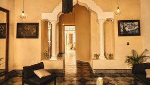 A lobby with a checkered floor, two sofas, a chandelier, and a framed painting. - Hotel Boutique Casa Jade (Campeche)