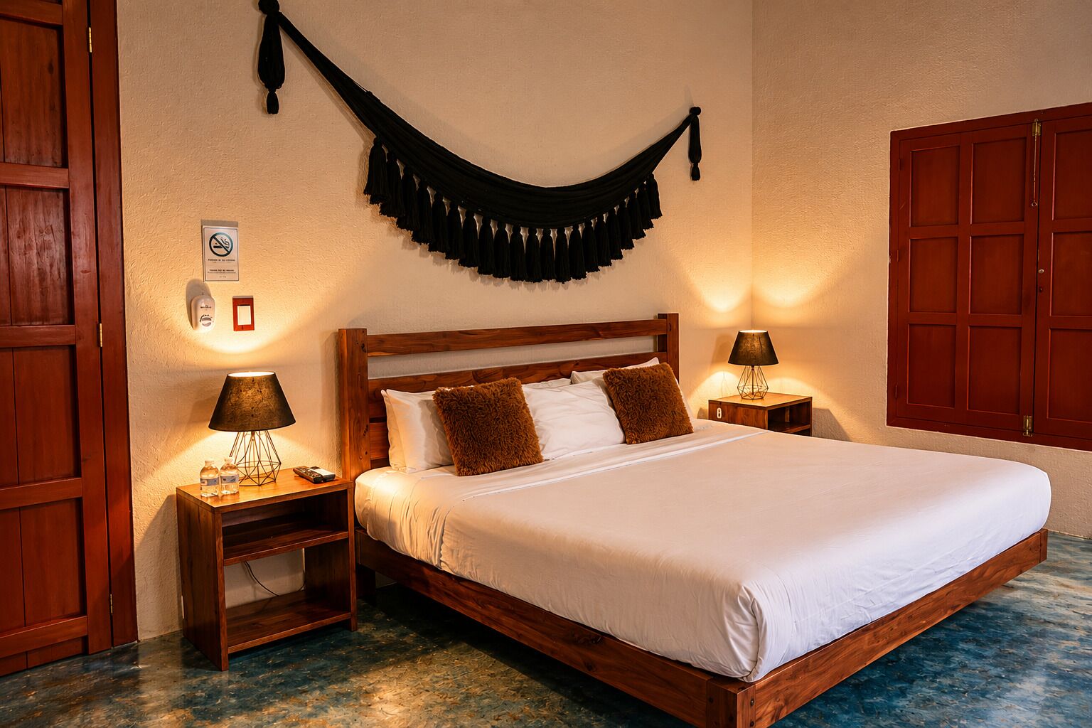 A hotel room with a wooden bed, two bedside tables with lamps, a wall-mounted black curtain, and a wooden wardrobe.