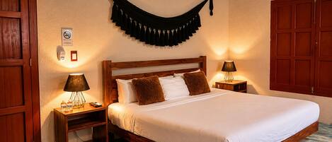 A hotel room with a wooden bed, two bedside tables with lamps, a wall-mounted black curtain, and a wooden wardrobe.
