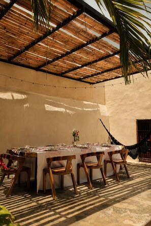 An outdoor dining area with a long table, wooden chairs, and a thatched roof. - Hotel Boutique Casa Jade (Campeche)