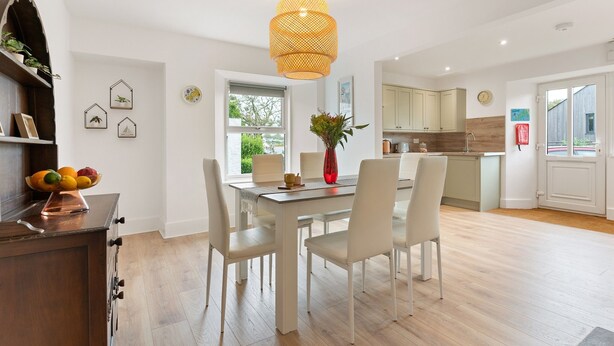 A modern kitchen with white cabinets, a wooden countertop, and a hanging light fixture. - Delightful Family Getaway Cornwall (Falmouth)