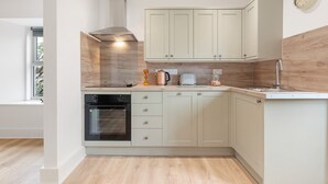 A modern kitchen with light-colored cabinets, a built-in oven, and a coffee maker. - Delightful Family Getaway Cornwall (Falmouth)
