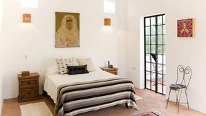 A bedroom with a bed, nightstands, a window, and artwork on the walls.