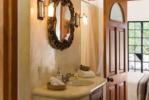A bathroom with a large mirror, a sink, and a door leading to a balcony.
