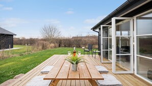 Una terrassa de fusta amb una taula de picnic, una planta en test i una ampolla de vi.