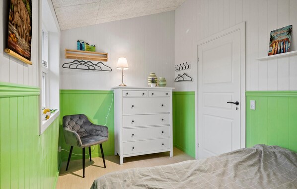 A bedroom with a bed, a dresser, a chair, and a door.