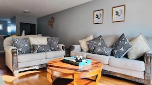 A living room with two sofas, a coffee table, and framed artwork on the wall.