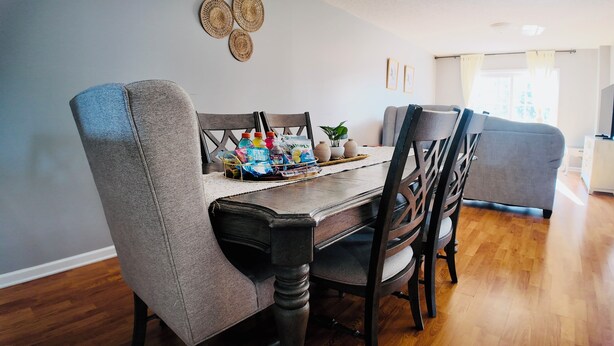 A dining area with a wooden table, grey upholstered chairs, and a tray with beverages and snacks.