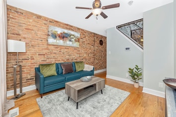 Living room with original exposed brick walls and original hardwood floors.