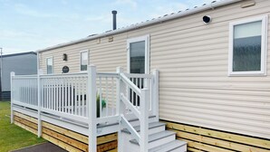 Una casa móvil con una terraza blanca y escalones de madera que llevan a una puerta.