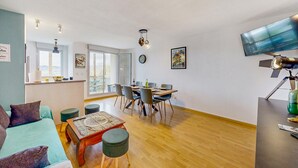 Ein modernes Wohnzimmer mit Sofa, Couchtisch und Essbereich mit Stühlen und einem Tisch.