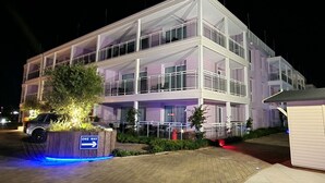 Un edificio moderno a più piani con facciata in vetro, un segnale di senso unico e un piccolo parcheggio con un'auto.