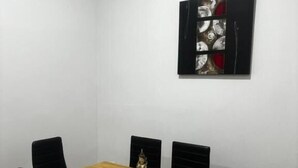 Un coin repas avec une table en bois et des chaises noires, une statue décorative et une œuvre d’art encadrée au mur.
