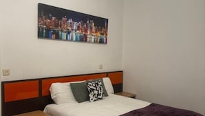 Une chambre à coucher avec un lit, des tables de chevet, un tableau représentant un paysage urbain et un luminaire au plafond.