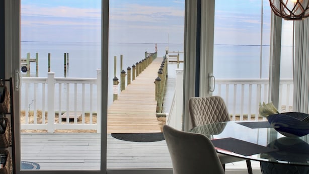 A view from a room with a glass door to a wooden deck leading to a pier.