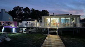 A waterfront property with a covered deck, a hot tub, and a sign that reads "LOVE".