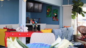 A room with a red desk, a blue sofa, and a television mounted on the wall.