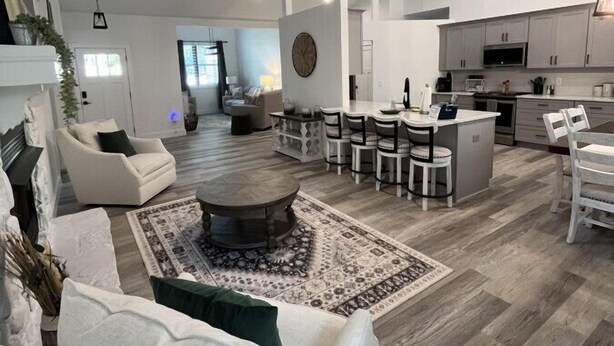 A spacious living room with a fireplace, a dining area, and a kitchen. - The Rhododendron Cottage (Franklin)