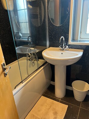 A bathroom with a bathtub, a sink, and a mirror. - Cozy Gogarstone Cottage in Newbridge (Newbridge)