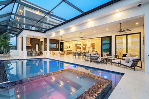 A modern indoor pool area with a glass ceiling, multiple seating areas, and a dining space. - Intervillas Florida - Villa Francabella (Cape Coral)