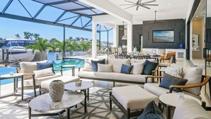 A modern living area with a pool, outdoor seating, and a view of boats.