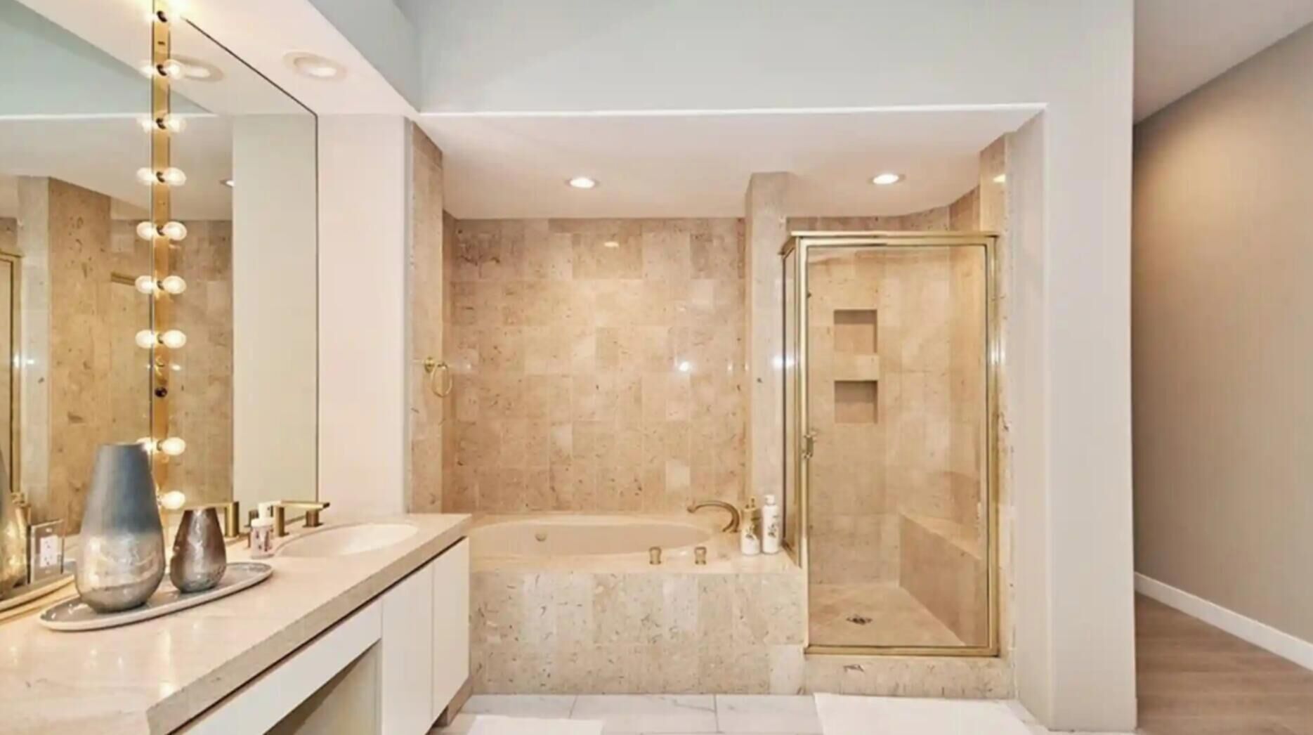 Une salle de bain moderne dotée d’un grand miroir, d’un meuble-lavabo, d’une baignoire et d’une douche à l’italienne.