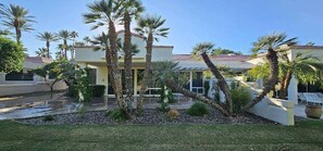 A residential property with a pool, palm trees, and a well-maintained lawn.
