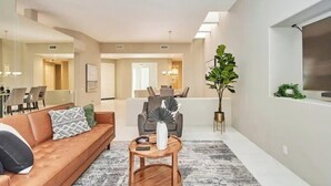 A modern living room with a sofa, coffee table, and a large plant.