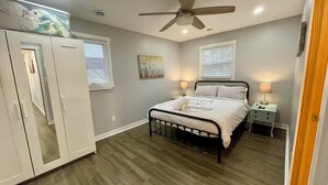 Una camera da letto con un letto, un ventilatore a soffitto, un armadio e un comodino con una lampada.