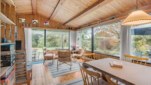 A wooden interior with a dining area, large windows, and a view of the garden. - 3 bedroom awesome home in Rødvig Stevns (Rødvig Stevns)