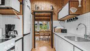 A compact kitchen with white cabinets, a built-in oven, a coffee maker, and a sink. - 3 bedroom awesome home in Rødvig Stevns (Rødvig Stevns)