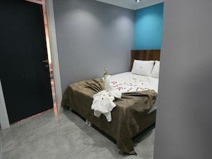 A modern hotel room with a bed, a nightstand, and a door.
