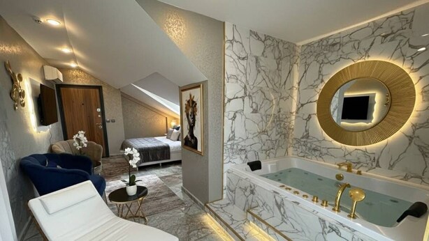 A modern bathroom with a marble floor, a freestanding bathtub, and a wall-mounted mirror. - Viyana Suite Hotel (Istanbul)