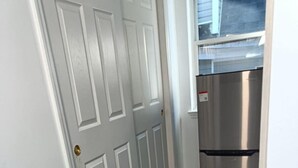 Une cuisine avec un réfrigérateur en acier inoxydable, une porte blanche et un plancher en bois foncé.