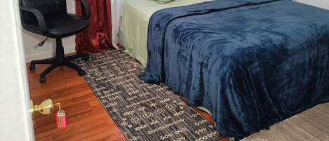 Une petite chambre à coucher, bien rangée, avec un lit, une chaise et un tapis à motifs.