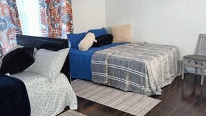 Une chambre avec deux lits, une chaise, un tableau et une fenêtre avec des rideaux.