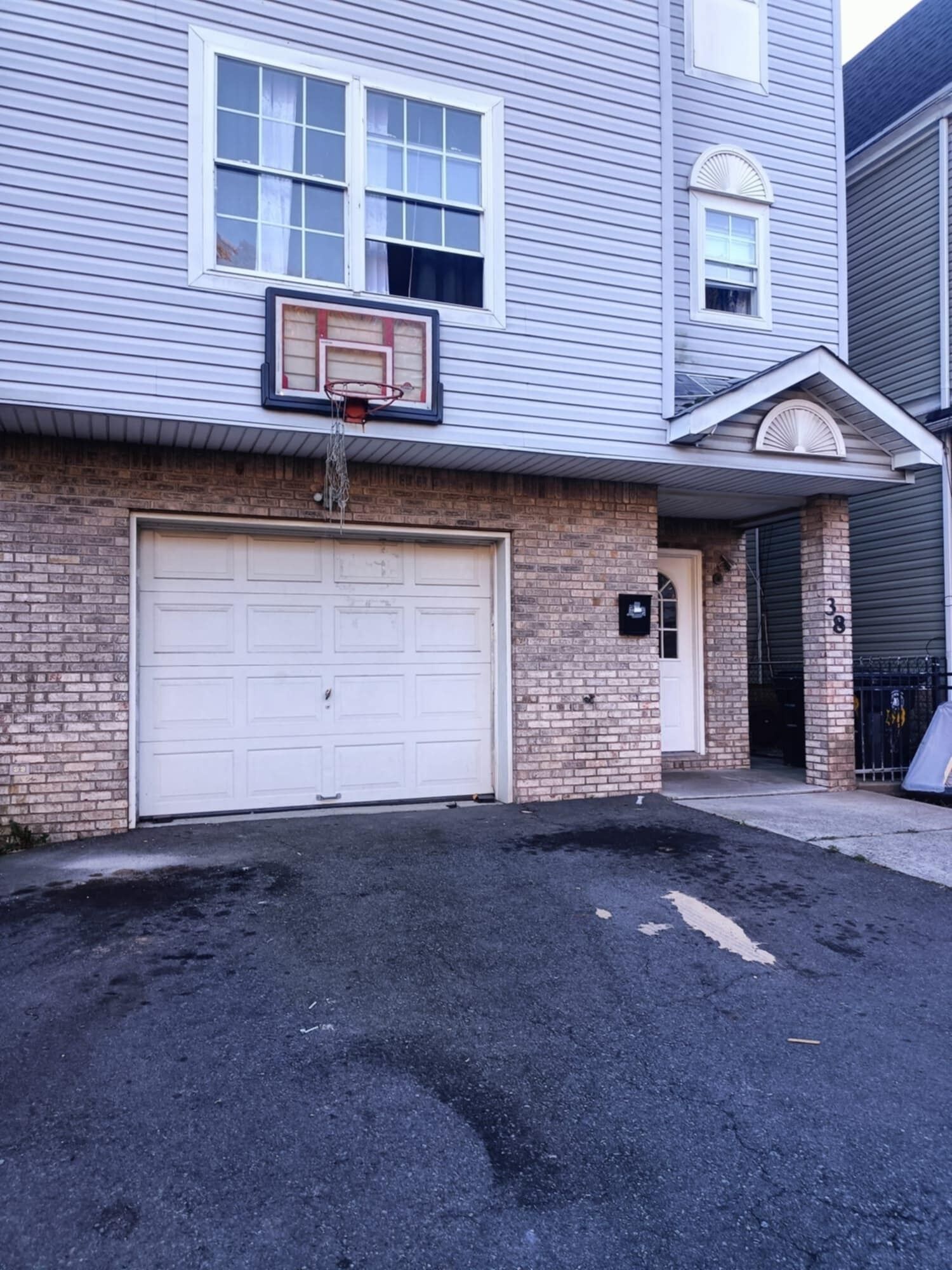 A two-story house with a garage door, a basketball hoop, and a brick facade.